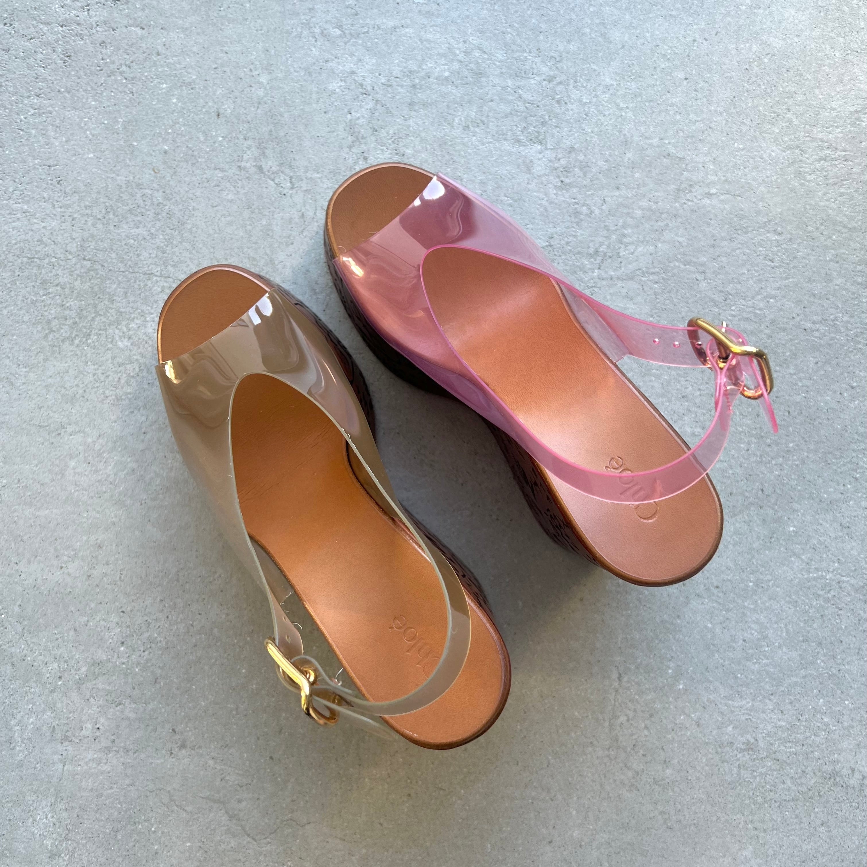 Pair of transparent sandals with pink straps on a light gray background
