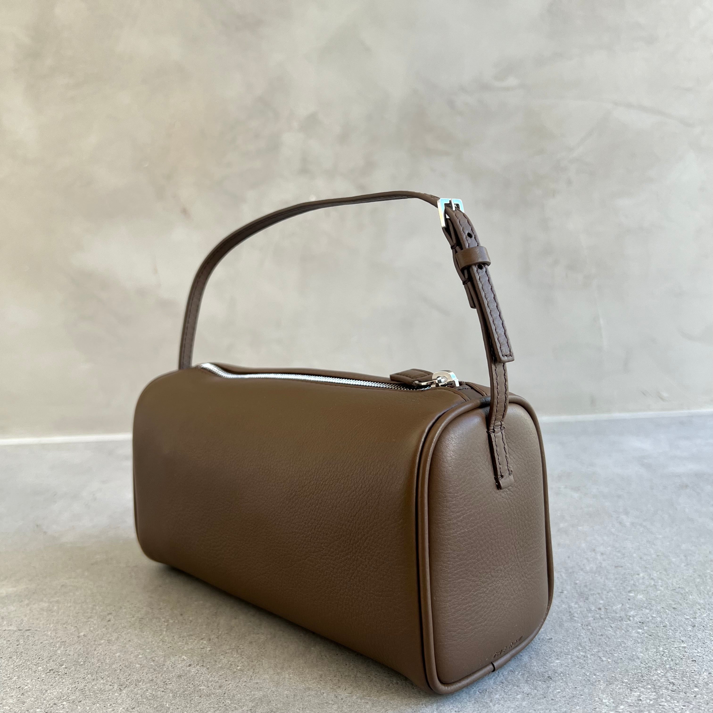 Brown handbag on a light gray surface with a neutral background