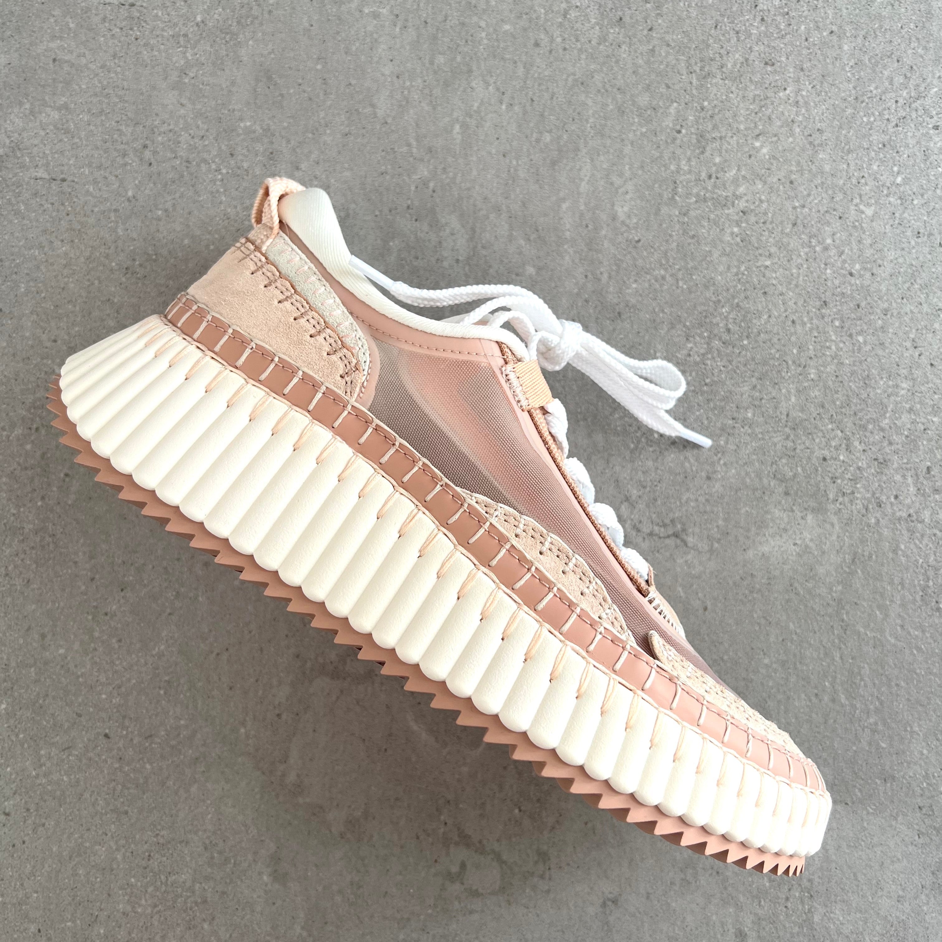 Pink sneaker with a thick white sole on a gray background