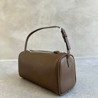 Brown handbag on a light gray surface with a neutral background